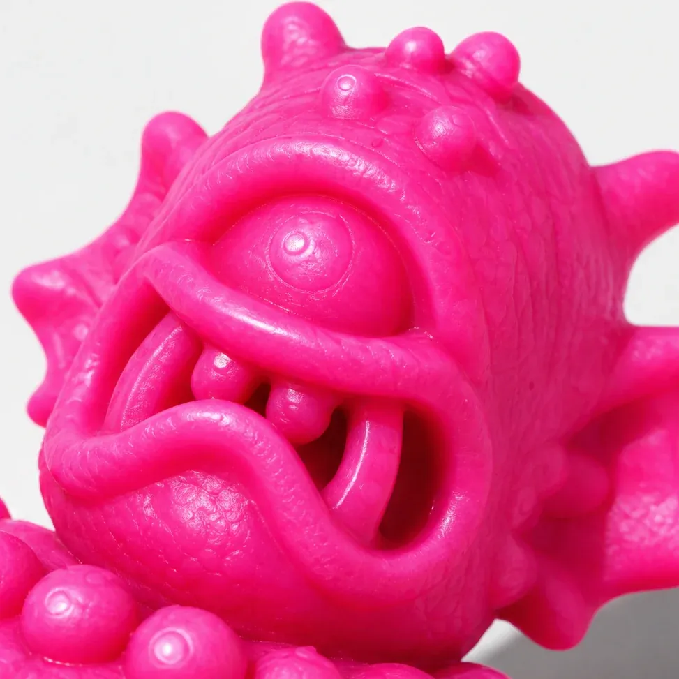 A close-up of the cyclops's face in hot pink, its one eye and its teeth.